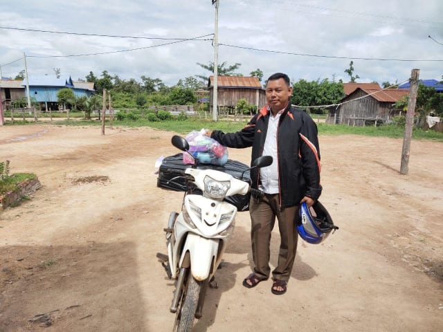 Mr Hy Sombo, one of our education officers in Cambodia, stands by his motorbike